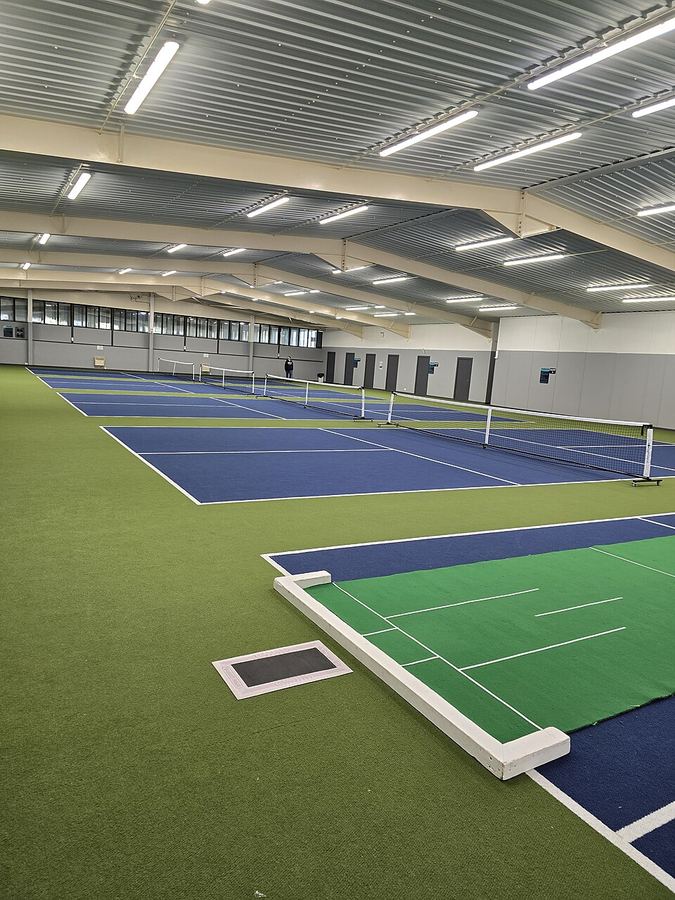 Indoor pickleball court with bright overhead lighting
